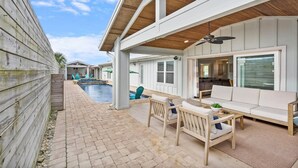 Une terrasse extérieure couverte avec une piscine, un espace salon et une vue sur la piscine.