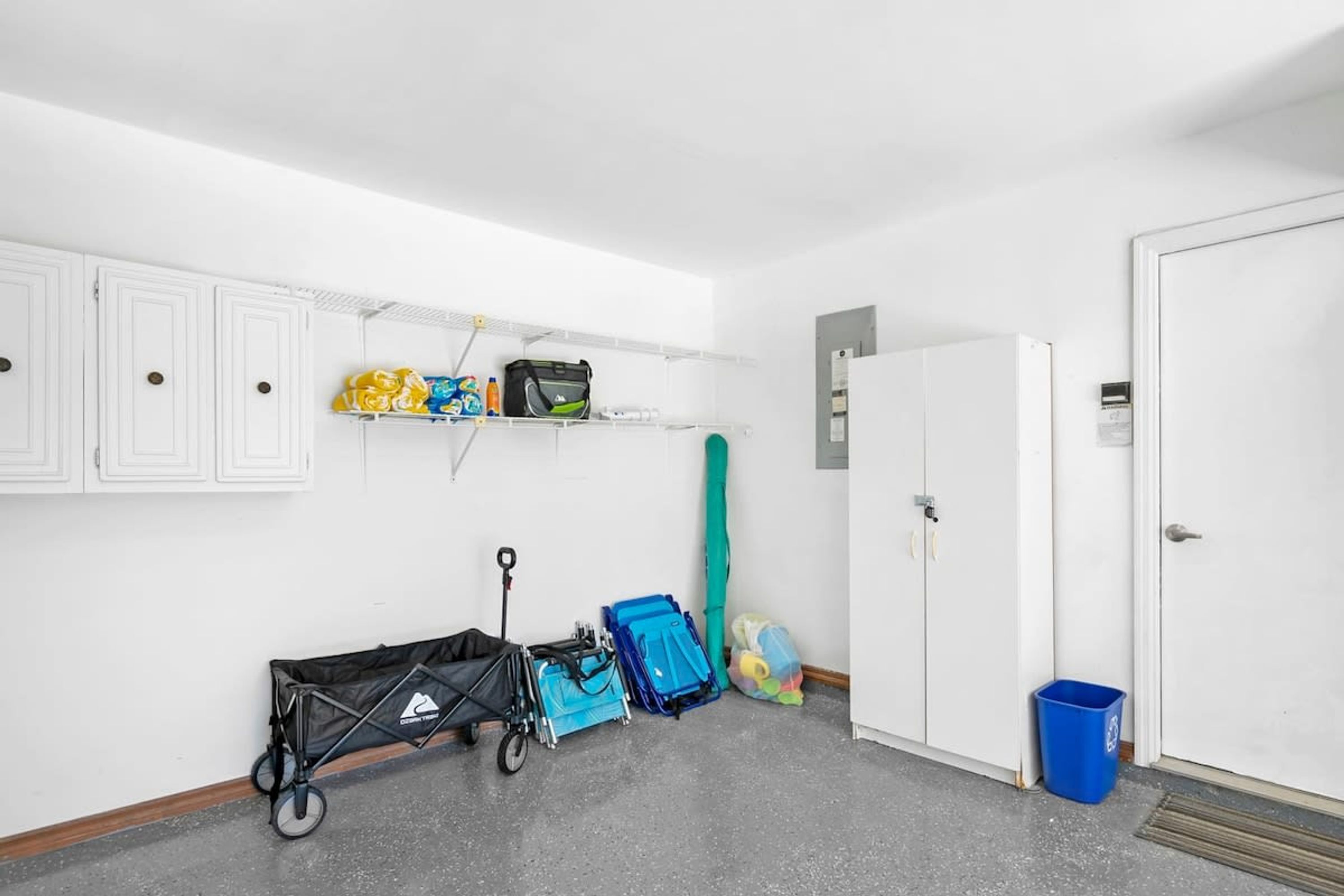 Ett rent, vitt rum med en dörr, en liten papperskorg och en barnvagn.