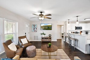 A modern living room with a brown leather sofa, a round coffee table, and a ceiling fan. - Water View Hot Tub Games Fire Pit Boat Parking (St. Augustine)