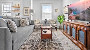 A living room with a grey sofa, patterned cushions, a coffee table, a TV, and a cabinet. - Free Parking Big Patio Next to Restaurants Bars (St. Augustine)