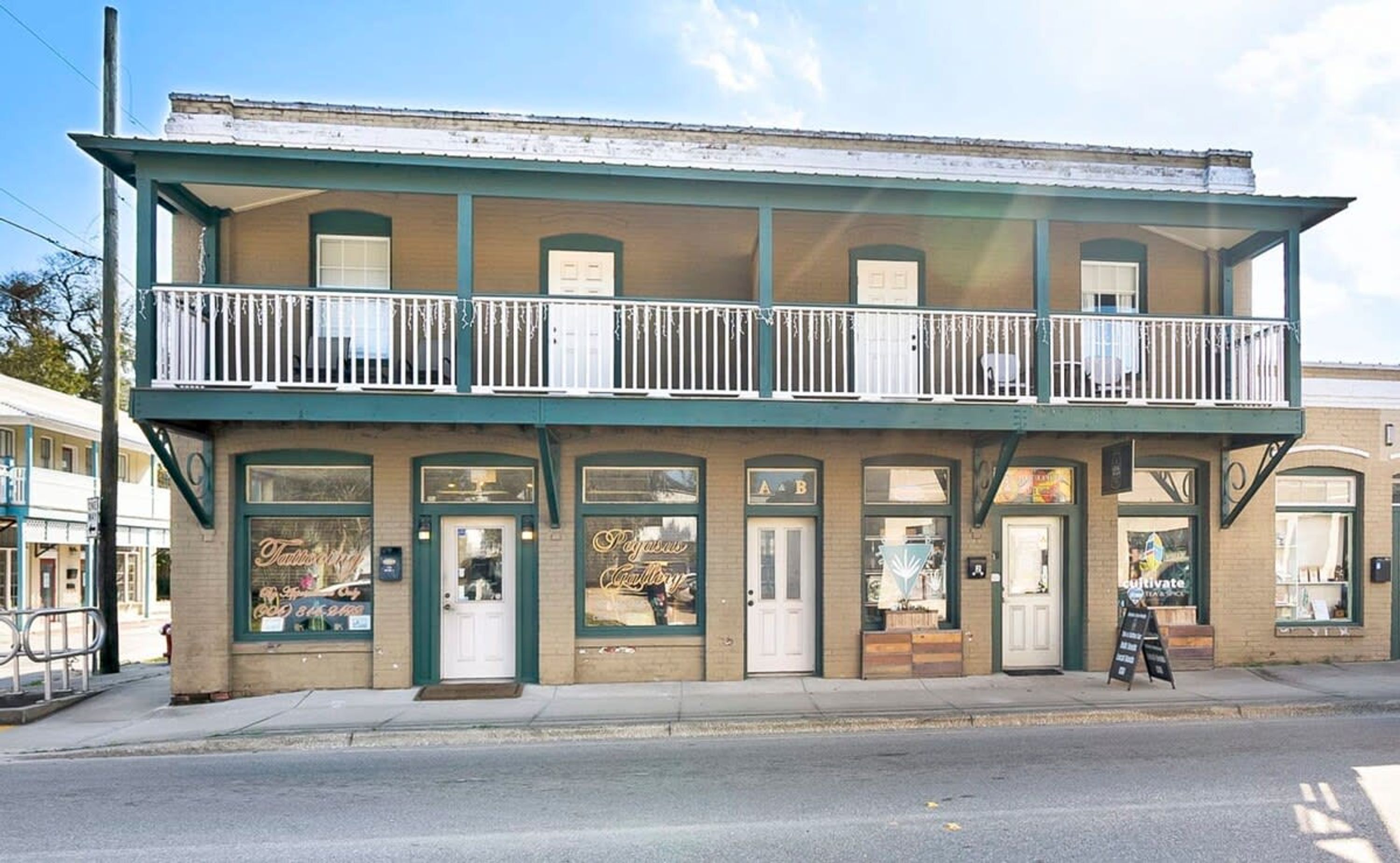 A two-story building with a balcony on the upper floor, featuring multiple doors and windows.
