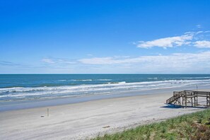 A beach with a wooden structure, likely a lifeguard stand, and a clear blue sky.