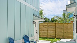 A patio with two blue chairs and a wooden fence. - Downtown St Augustine Apt Smart TV Pack N Play (St. Augustine)