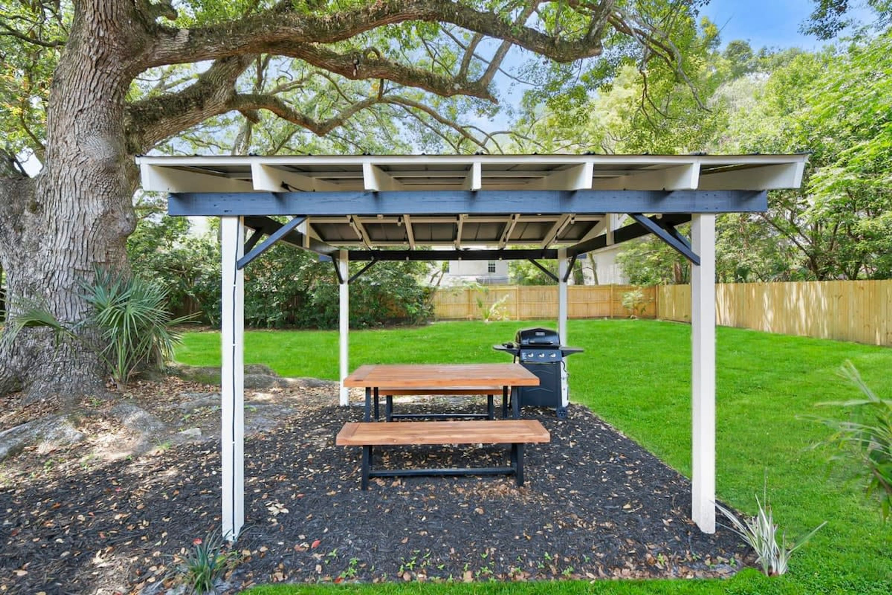 Ein überdachter Außenbereich mit Picknicktisch und Grill.