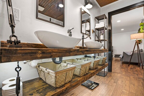 Une salle de bain moderne avec un grand lavabo sur pied, plusieurs paniers de rangement et un meuble-lavabo en bois.