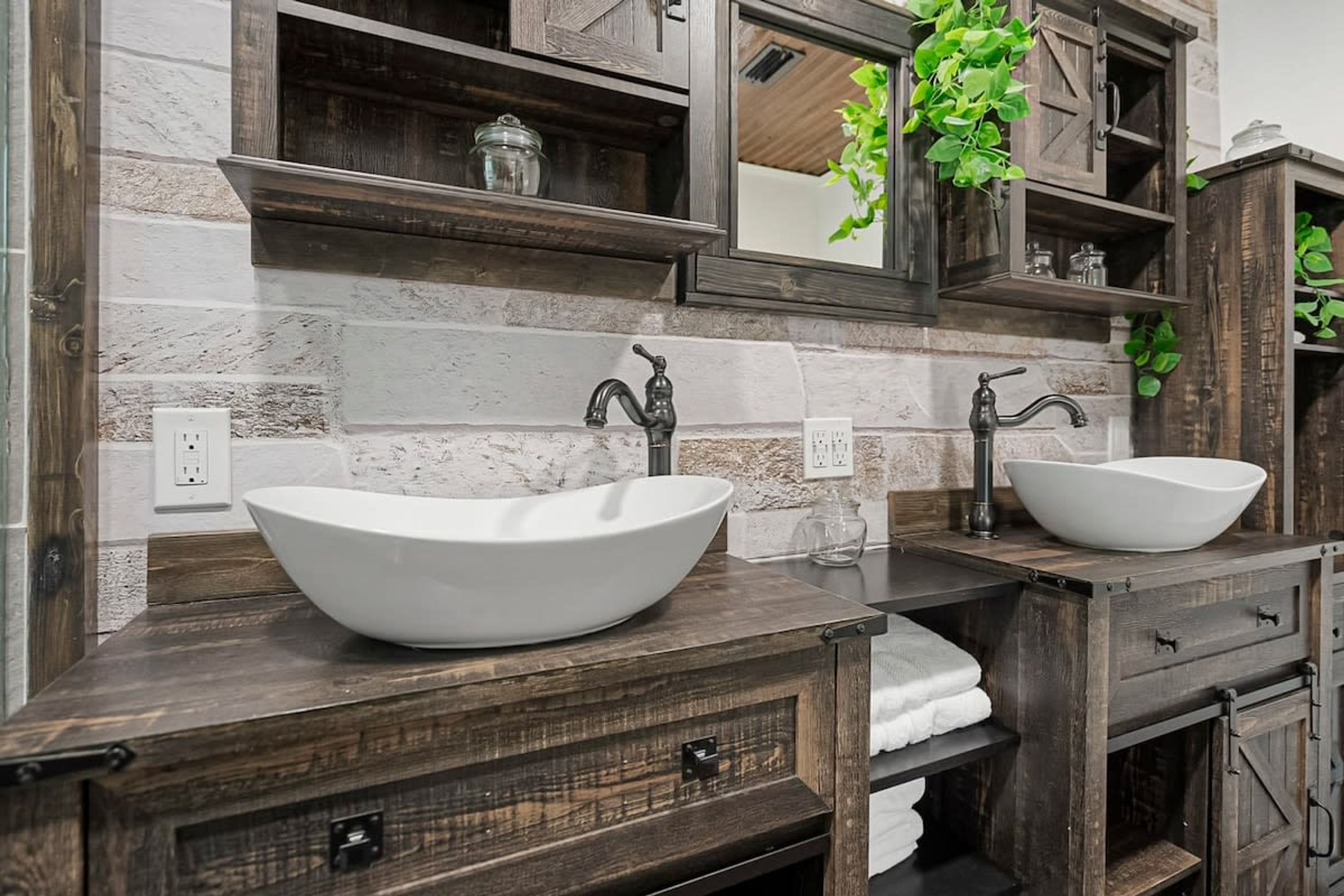 A bathroom with a large white vessel sink, dark wooden vanity, and a mirror above the sink.