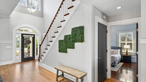 Un hall d’entrée spacieux avec un escalier en bois, un banc et une porte donnant sur une chambre.