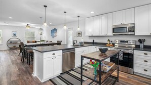 A modern kitchen with white cabinetry, stainless steel appliances, and pendant lighting. - Pool Spa Downtown by Beach FOY Add Golf Cart (St. Augustine)