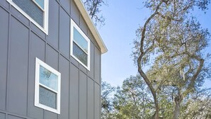 An outdoor patio with white furniture, a fire pit, and a view of a house with large windows and a tree. - Pool Spa Downtown by Beach FOY Add Golf Cart (St. Augustine)
