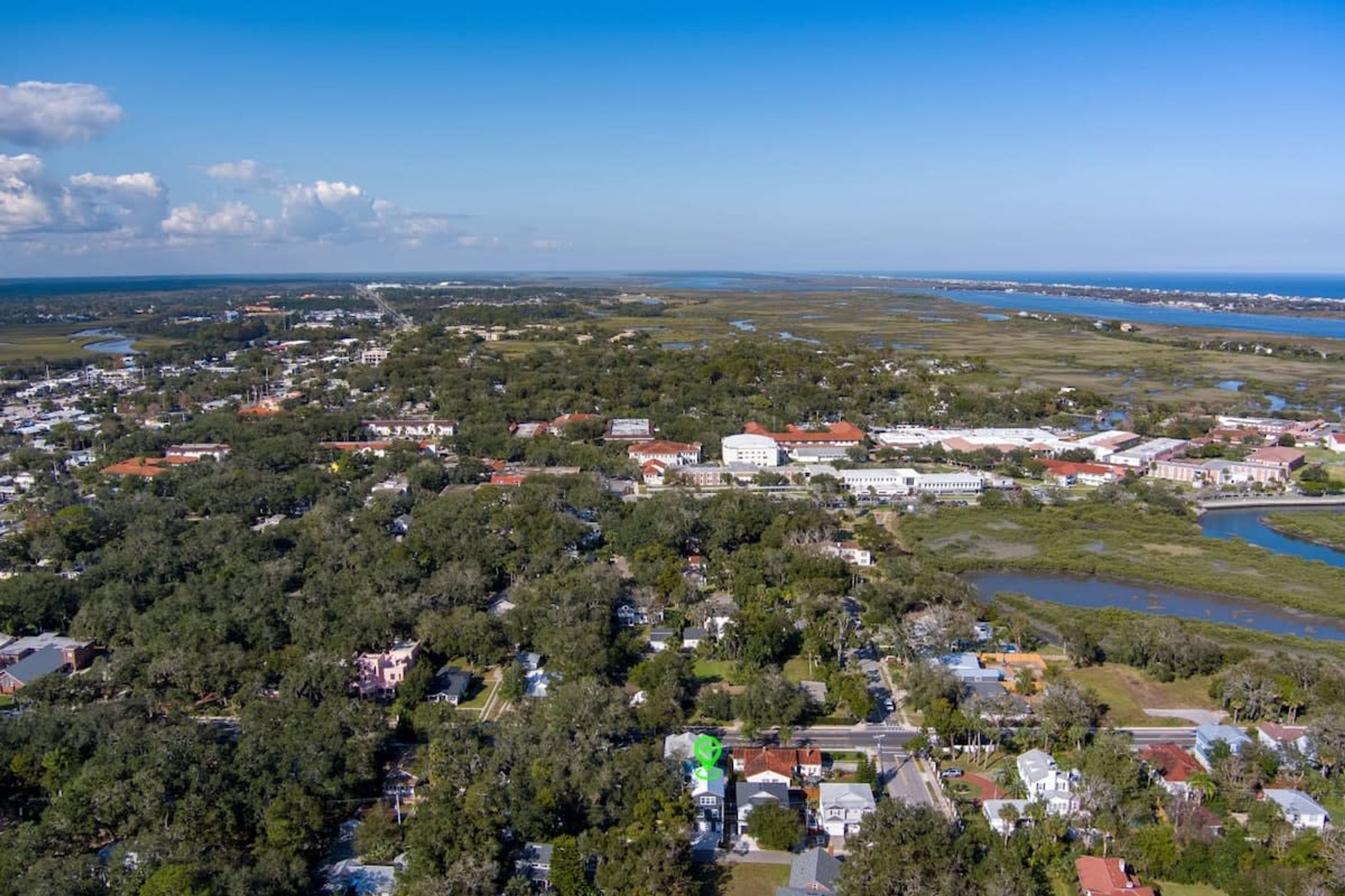 An aerial view of a coastal town with residential areas, a large white building, and a river.