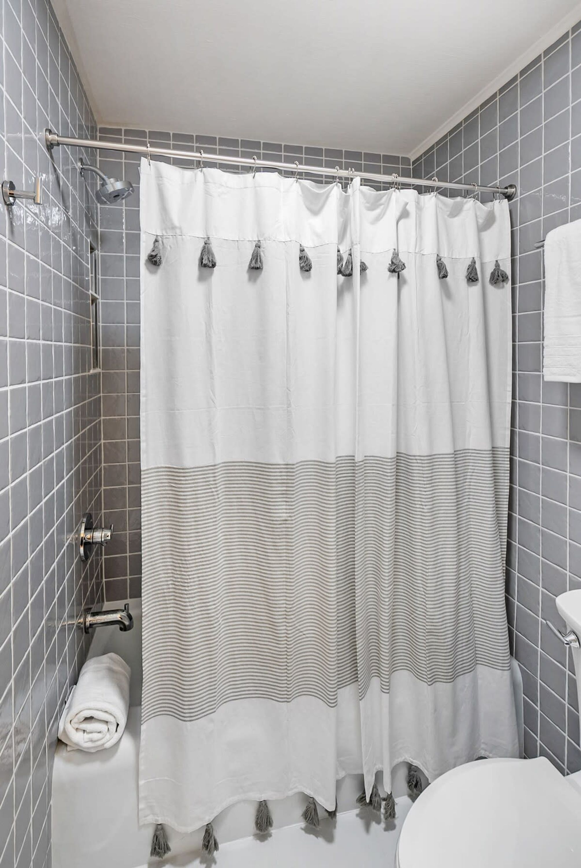 Une salle de bain avec un rideau de douche, un porte-serviettes et des toilettes.