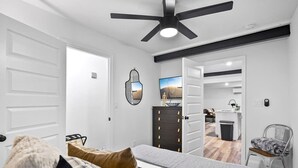 Une chambre à coucher avec un lit, une commode, un miroir et un ventilateur de plafond.