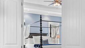 Ein Schlafzimmer mit einem Himmelbett, einem Deckenventilator und einem Nachttisch.