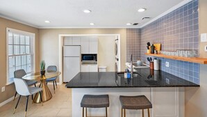 Cozinha moderna com bancada preta, armários brancos e painel de azulejos.