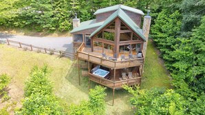 A two-story log cabin with a wrap-around deck, a hot tub, and a stone chimney. - Hot Tub 3 Fireplaces Mountain Views Game Room (Blue Ridge)