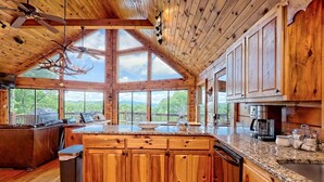 A spacious kitchen with wooden cabinets, granite countertops, and large windows offering a view of the outdoors. - Hot Tub 3 Fireplaces Mountain Views Game Room (Blue Ridge)