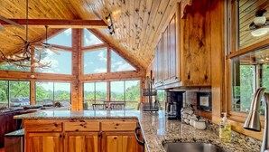 A spacious kitchen with wooden cabinets, granite countertops, and large windows offering a view of the outdoors. - Hot Tub 3 Fireplaces Mountain Views Game Room (Blue Ridge)