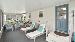 A covered outdoor seating area with white lounge chairs and a blue door. - Qt Cottage on Dunn s Creek Fire Pit Kayaks (Satsuma)