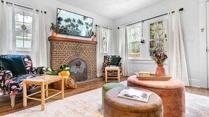 Een woonkamer met een schouw van baksteen, een bank, een fauteuil en een salontafel.