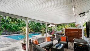 An outdoor patio with a pool, wicker furniture, and a grill area. - Welcome Basket Pool By Beach Fire Pit BBQ PS4 (St. Augustine)