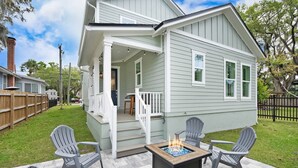 Ein Haus mit überdachter Veranda, Feuerstelle und Sitzgelegenheiten im Freien.