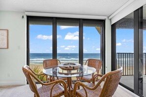A balcony with a glass table and wicker chairs, overlooking the ocean. - Vast Oceanfront Views Pool Patio Tennis (St. Augustine)