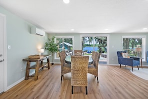 Un coin repas avec des chaises en osier, une table en bois et une vue sur l’extérieur.