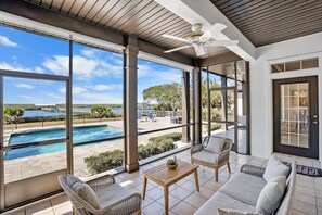 A covered outdoor seating area with a view of a swimming pool and a landscaped garden. - Waterfront Home w Patio Heated Pool Dock Beach (St. Augustine)