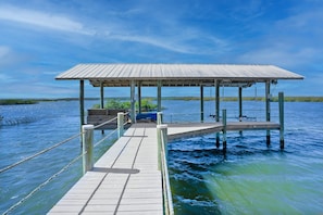 A wooden dock extending into a body of water, supported by wooden posts and a metal railing. - Waterfront Home w Patio Heated Pool Dock Beach (St. Augustine)
