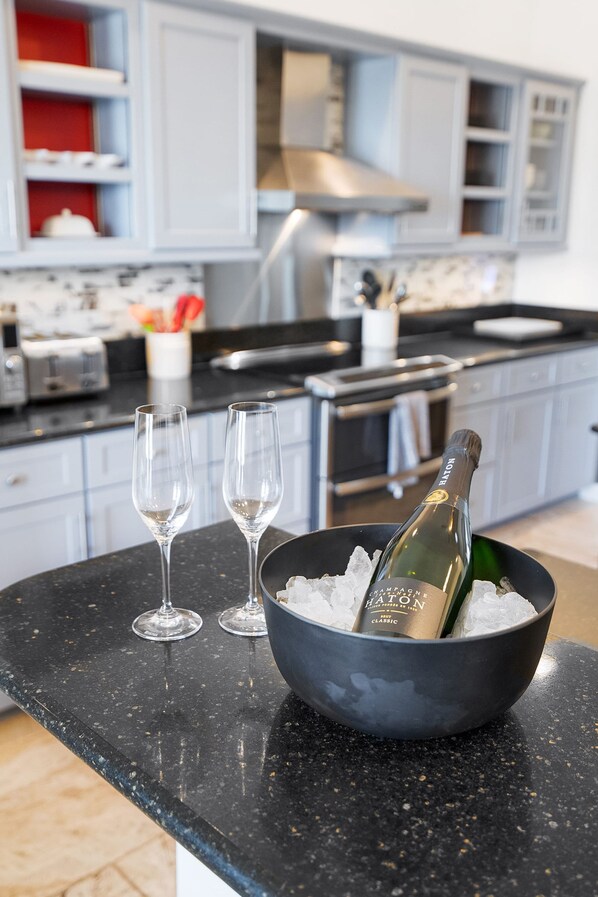 A kitchen counter with a bowl containing a bottle of champagne and two glasses. - Waterfront Home w Patio Heated Pool Dock Beach (St. Augustine)
