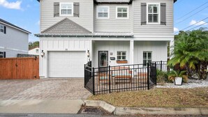 A two-story house with a garage, a front porch with a bench, and a small garden area. - Magnolia Ave Downtown By Beach Kids Playset (St. Augustine)
