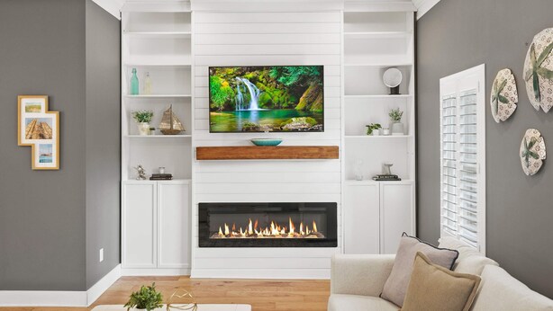 A living room with a fireplace, a mounted TV, and a white entertainment unit with shelves. - Magnolia Ave Downtown By Beach Kids Playset (St. Augustine)