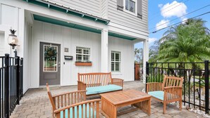A white building with a porch, wooden furniture, and a black gate. - Magnolia Ave Downtown By Beach Kids Playset (St. Augustine)