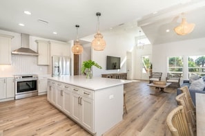 A spacious kitchen with white cabinetry, a central island, and pendant lighting. - Your Summer Haven Pool Games Near Beach (St. Augustine)