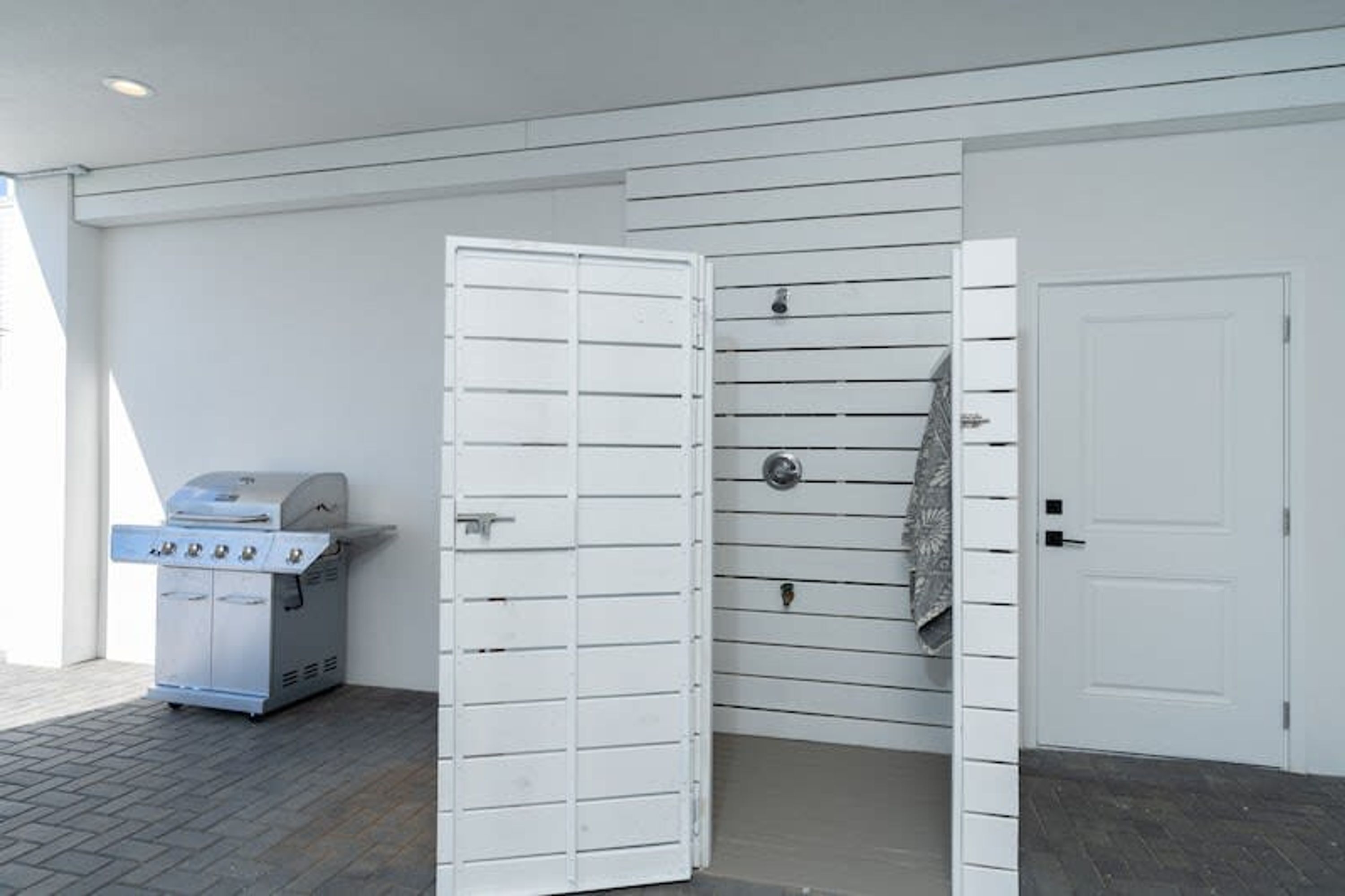 Un garaje con una parrilla, una puerta blanca y una pared con líneas horizontales.