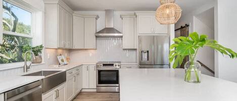 Una cocina moderna con armarios blancos, electrodomésticos de acero inoxidable y una isla grande.