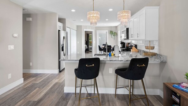 A modern kitchen with two black bar stools, a marble countertop, and pendant lights. - 5 Minutes to Beach and Downtown Fire pit Grill (St. Augustine)