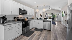 A modern kitchen with white cabinets, stainless steel appliances, and a large island. - 5 Minutes to Beach and Downtown Fire pit Grill (St. Augustine)