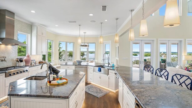 A spacious kitchen with a central island, large windows, and a view of the outdoors. - 400 Steps to Sand Waterfront Luxury w Dock Pool (St. Augustine)