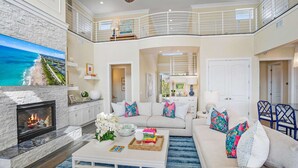 A spacious living room with a fireplace, a large TV, and a balcony with a railing. - 400 Steps to Sand Waterfront Luxury w Dock Pool (St. Augustine)