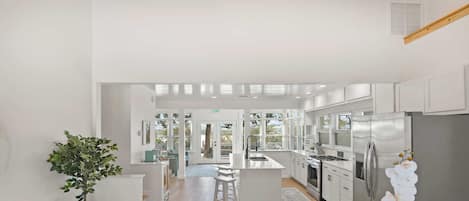 A modern kitchen with a central island, stainless steel appliances, and a view to the outdoors.
