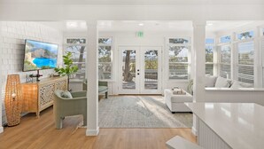 A modern hotel lobby with a white color scheme, a large flat-screen TV on the wall, a reception desk, and a seating area with a sofa and chairs. - Waterfront Incredible Views Fire pit Renovated (St. Augustine)