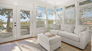 A spacious living room with a large window, a white sofa, and a small ottoman. - Waterfront Incredible Views Fire pit Renovated (St. Augustine)