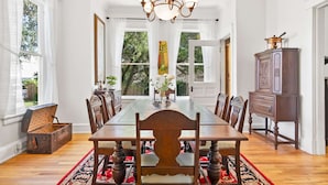 A dining room with a large wooden table, chairs, a chandelier, and a cabinet. - Historic in Downtown St Aug Steps to Ice Plant (St. Augustine)