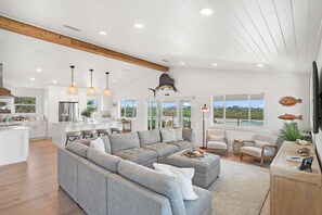 A spacious living area with a grey sectional sofa, a wooden dining table, and a kitchen in the background. - Dolphins and Dream Water Views Dock Your Boat (St. Augustine)