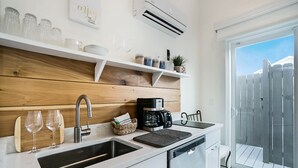 A modern kitchen with a wooden backsplash, a coffee maker, and a dishwasher. - 100 Steps to Beach Deck w Ocean View Beach Gear (St. Augustine)