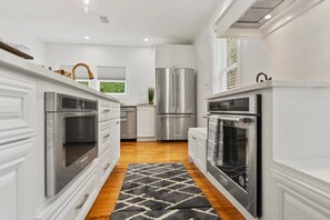 A modern kitchen with white cabinetry, stainless steel appliances, and a patterned rug. - Stay in A Castle In St Augustine Hot Tub Fireplace (St. Augustine)