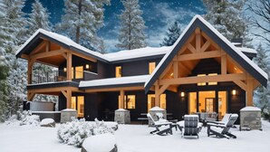 A large, multi-story lodge with a prominent wooden structure, outdoor seating area, and snow-covered surroundings.