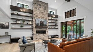 A modern living room with a stone fireplace, built-in shelves, and a leather sofa.