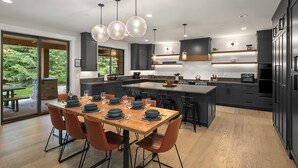 A modern kitchen with a central island, dark cabinetry, and pendant lighting.